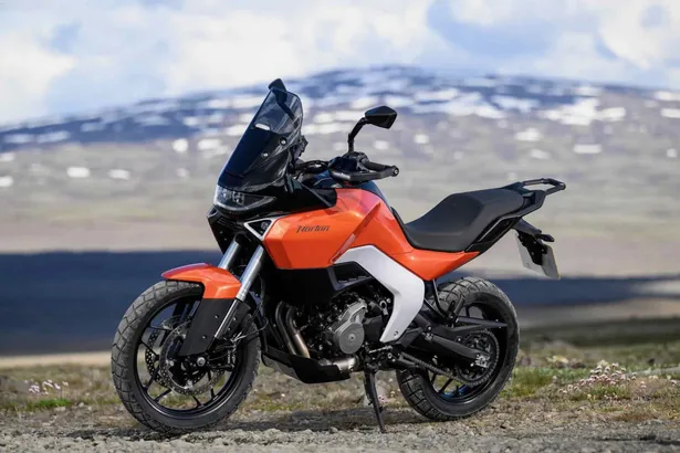 Karli dagin onunde duran turuncu adventure motosiklet.