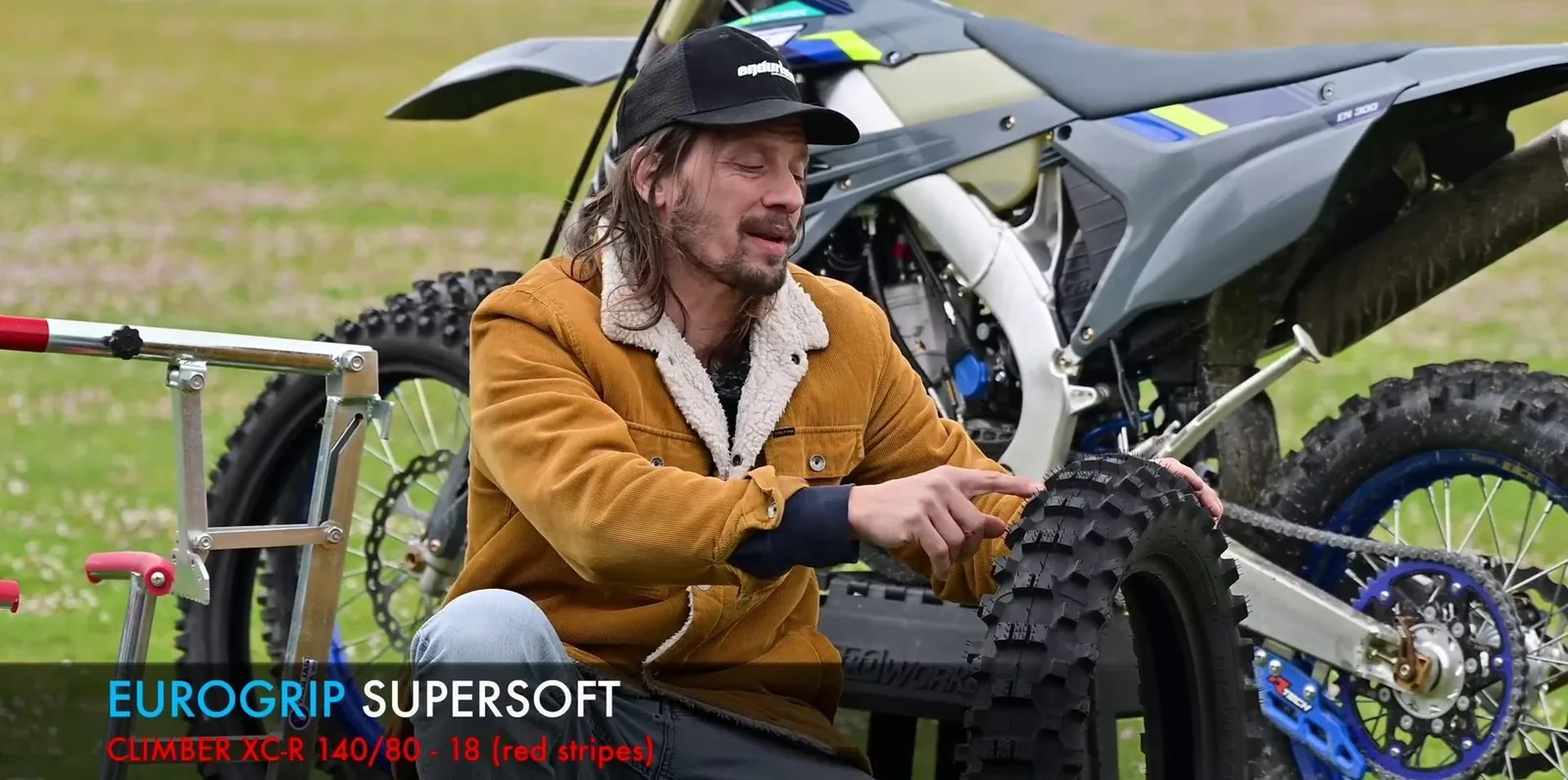 Yaris oncesi enduro motosikletinin lastigini kontrol eden bir surucu.