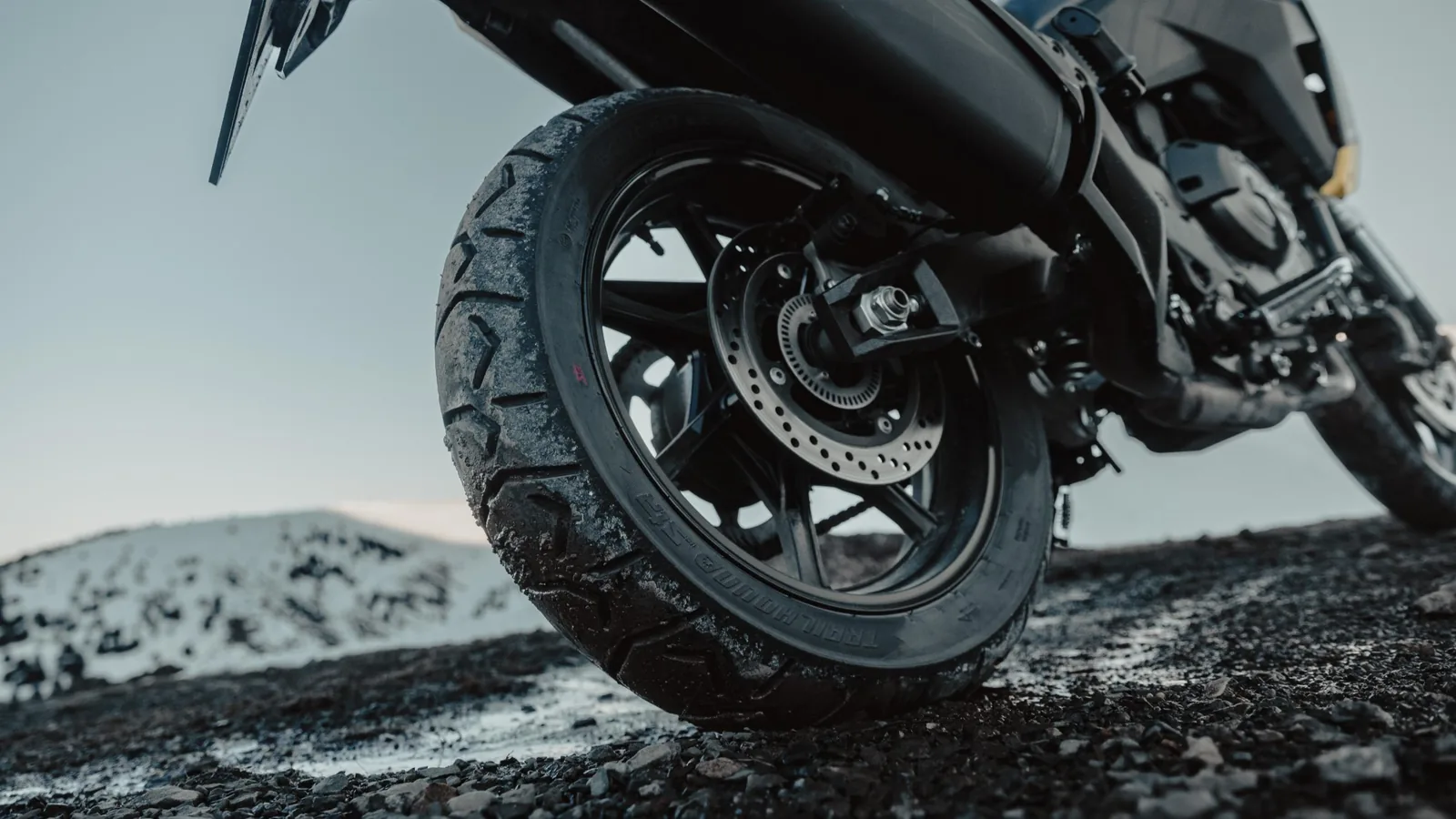 Tozlu bir toprak yolda ilerleyen adventure motosiklet.