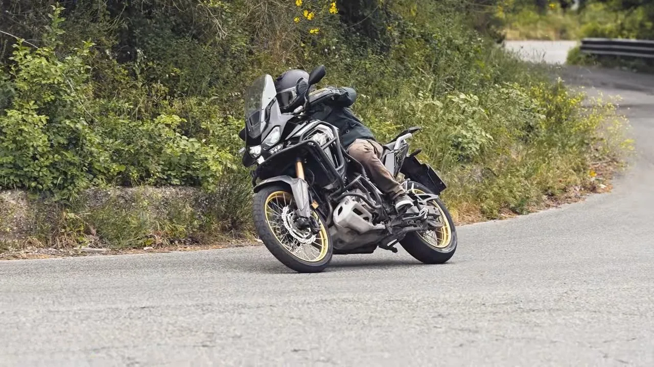 Asfalt bir virajdan cikan motosiklet, uzaktan.