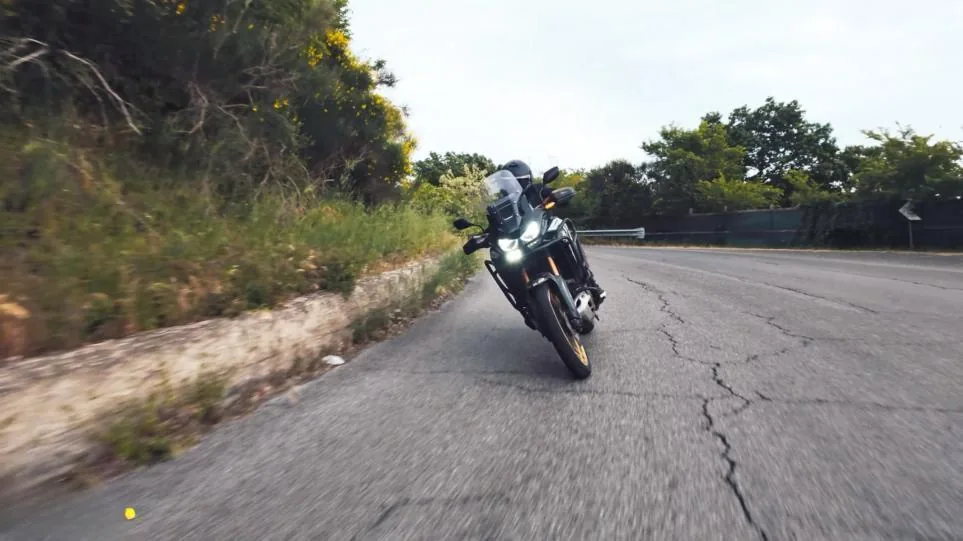 Catlakli asfaltta karsidan yaklasan adventure motosiklet.