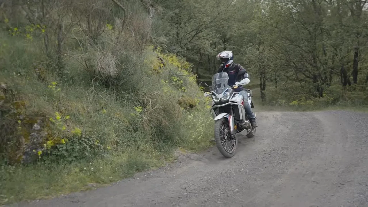 Yesillik arasindan gecen cakil yolda adventure motosiklet.