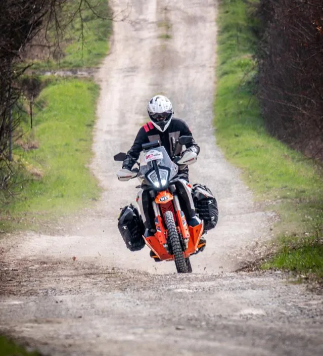 Cift izli toprak yolda karsidan gelen yuklu adventure motosiklet.